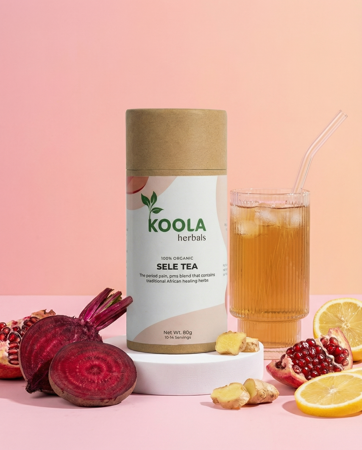 Koola herbals Sele Tea can with a glass of iced tea, pomegranate, lemon, and ginger on a pink background